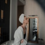 woman in white robe standing in front of mirror
