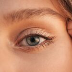 Detailed close-up of a human eye with visible eyelashes, skin texture, and natural lighting.