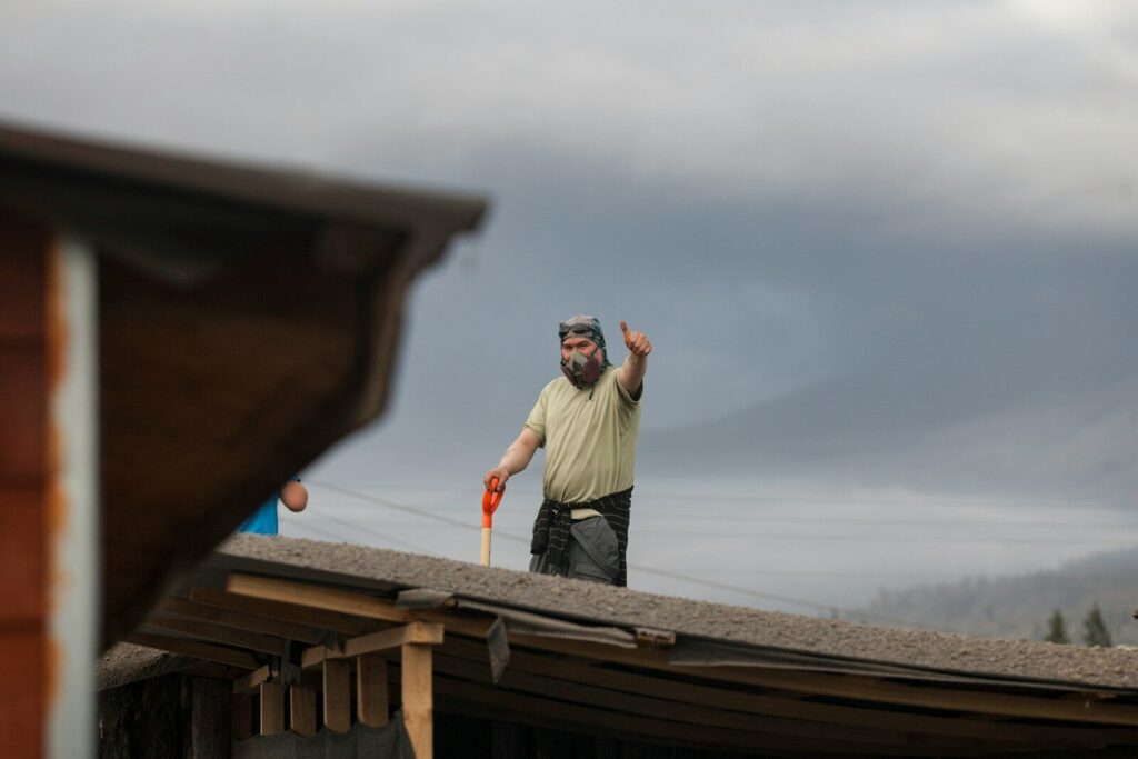 Man on roof waving with shovel