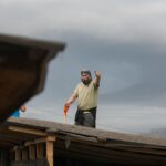 Man on roof waving with shovel