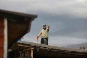 Man on roof waving with shovel
